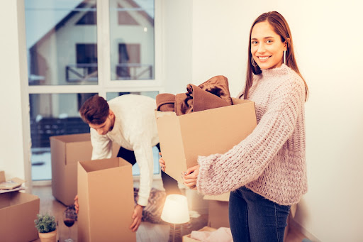 Woman holding a box full of belongings while moving in the winter.