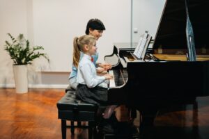 Young student learning from teacher how to play Grand Piano.