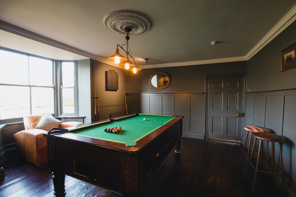 In-home pool hall with a large and bright window nearby