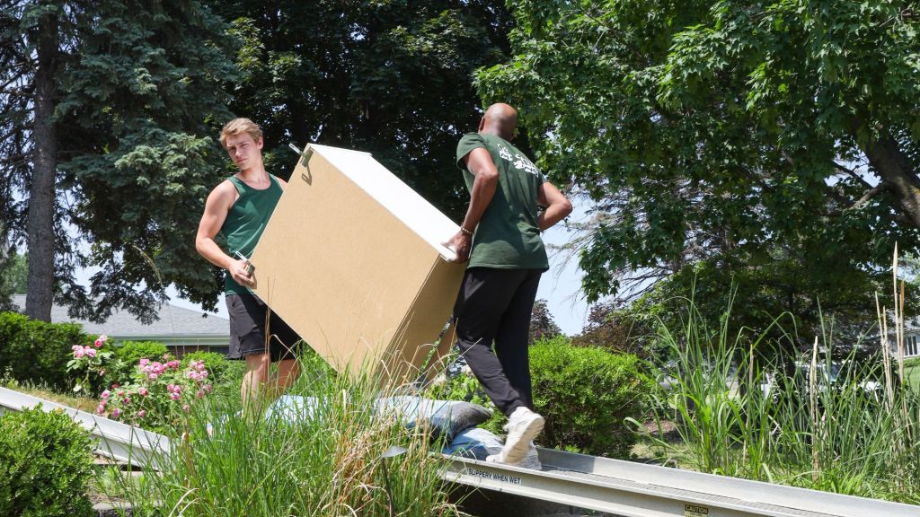 two good sutff moving crew members carrying a large box