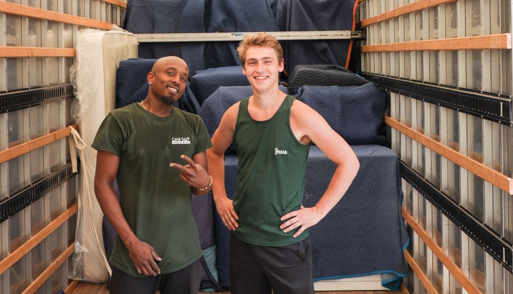 two good stuff movers standing side by side in the back of a moving truck