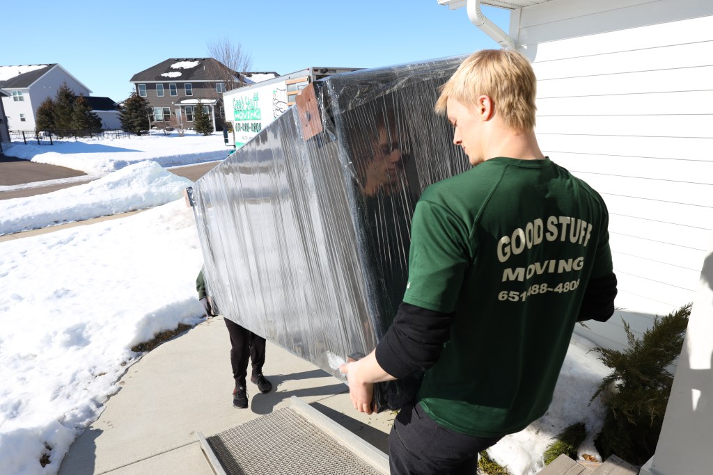 Two Good Stuff movers carrying a large piece of furniture