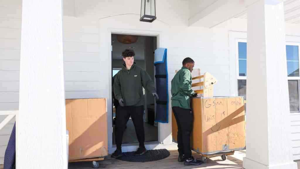 Two Good Stuff movers loading items into carts outside of a house