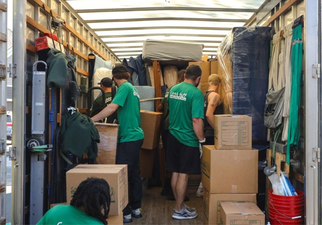 Six Good Stuff movers unloading boxes from the back of a moving truck
