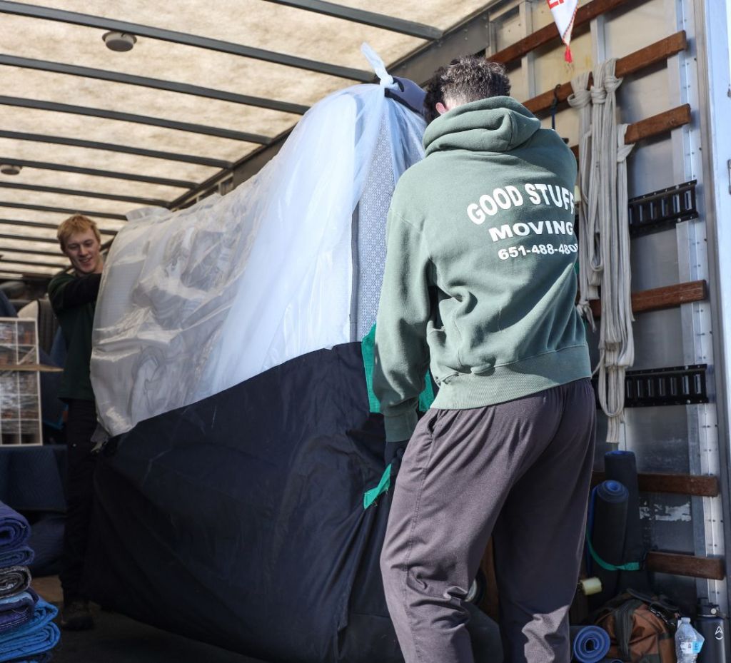 Two movers carrying a mattress out of a moving truck