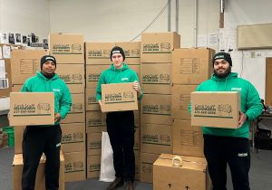 Three Good Stuff movers holding boxes in a room