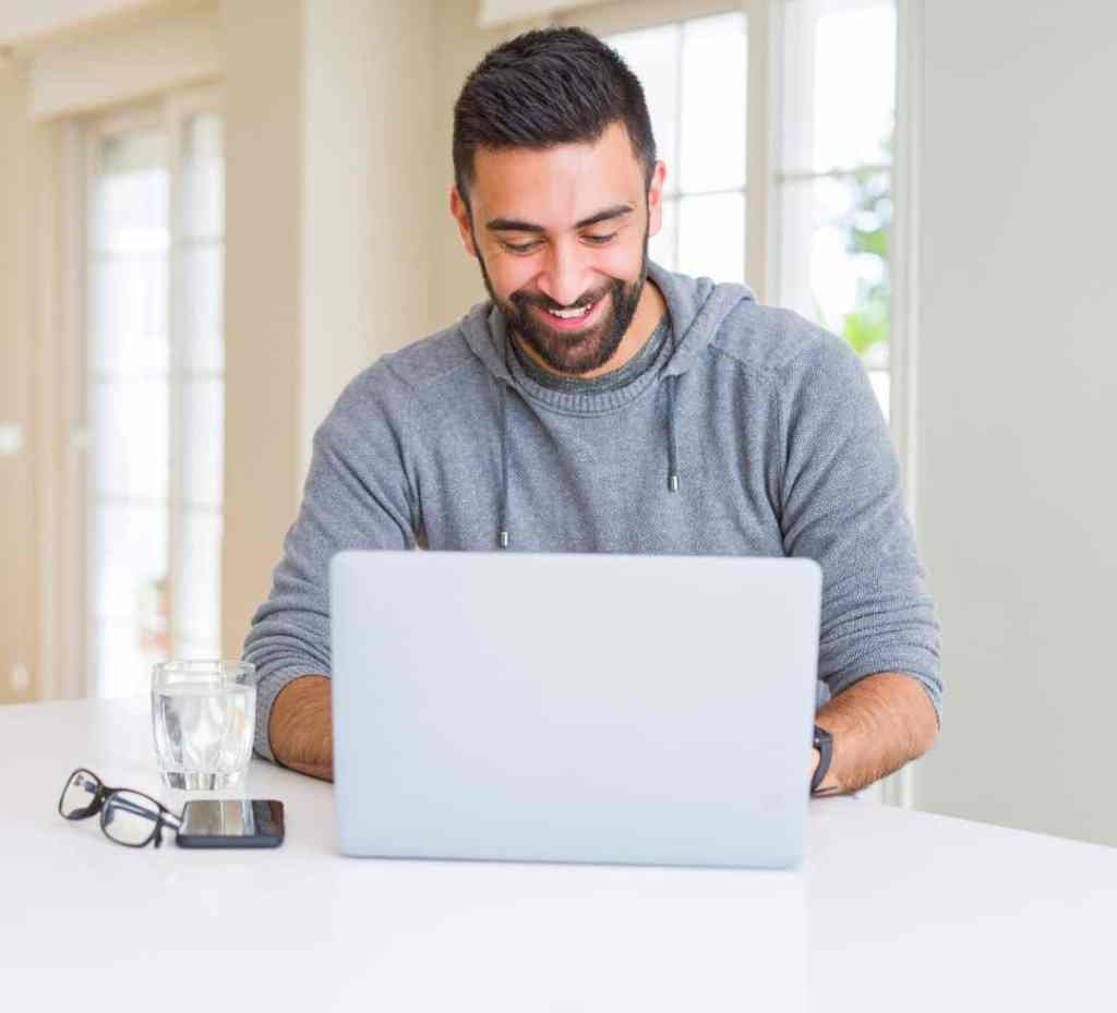man smiling while working on his laptop