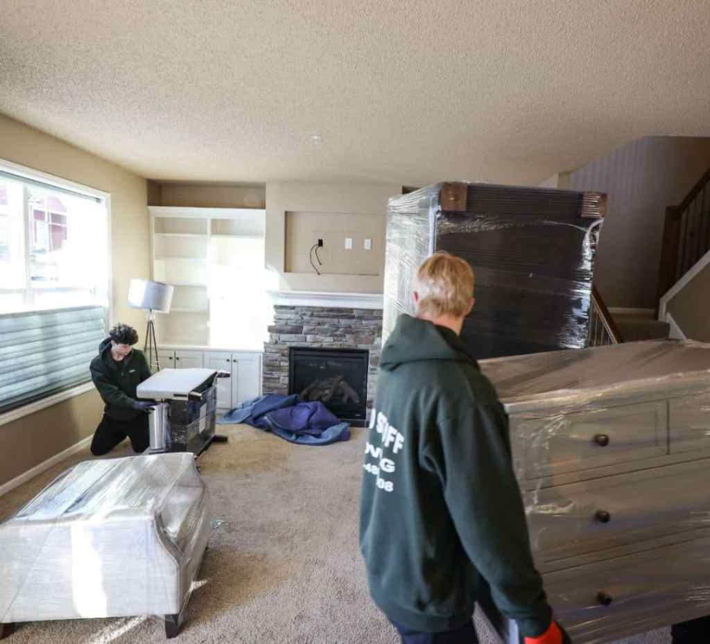 a group of professional movers wrapping furniture in shrink wrap