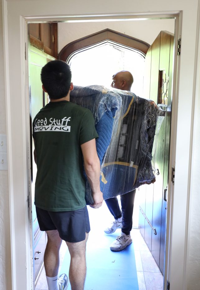 long distance movers carrying a piece of furniture out of the door