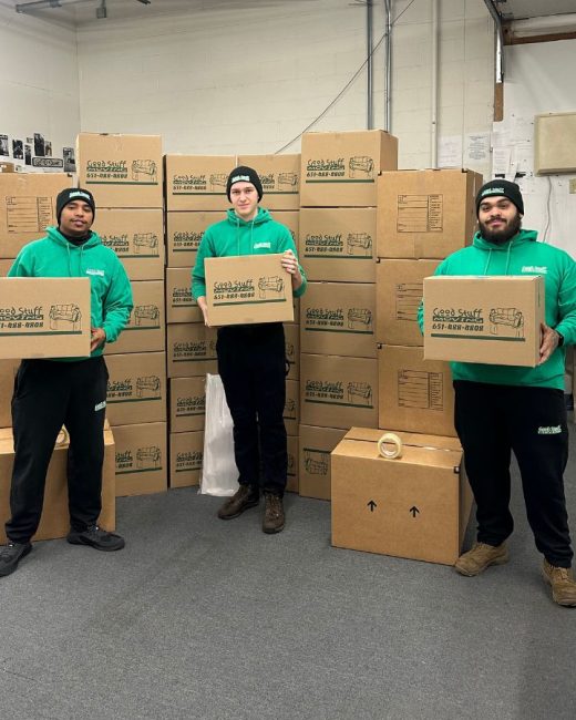 Three Good Stuff movers holding Good Stuff Moving boxes in a room