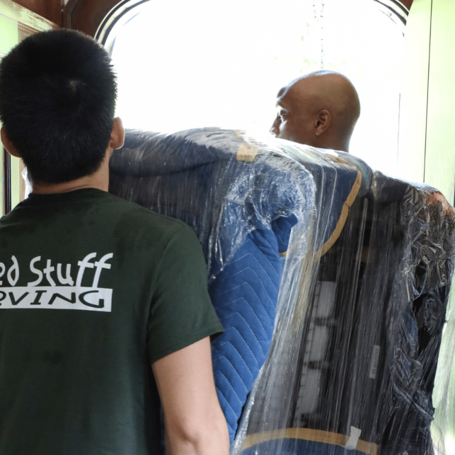 Good Stuff Moving crew carrying padded furniture through a doorway