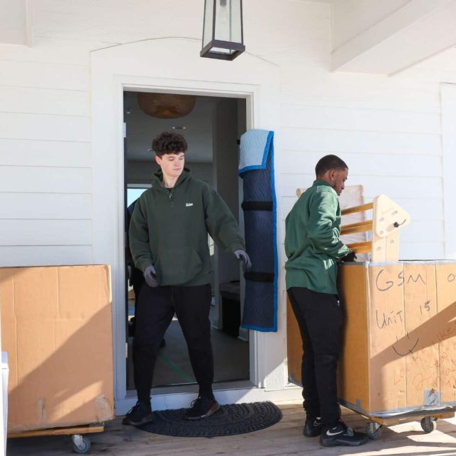 Two Good Stuff movers loading items into carts outside of a house